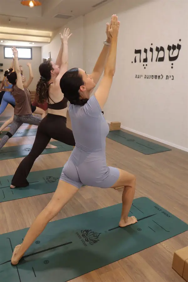 מתרגלות בתנוחת לוחם מול קיר הלוגו