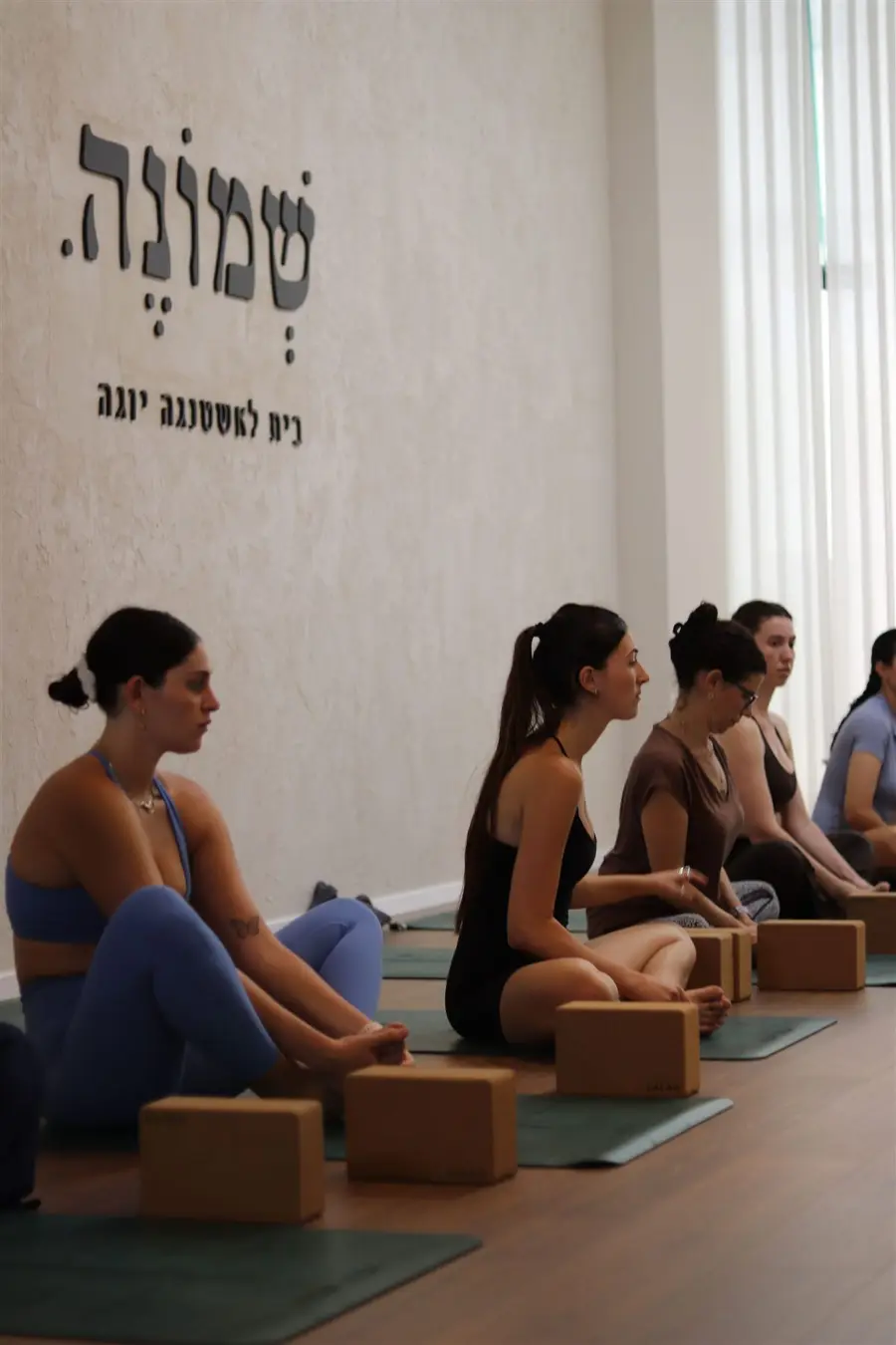 מתרגלות בשיעור לצד קיר הלוגו של שמונה במודיעין